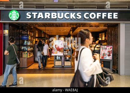 Fußgänger vorbei an einer amerikanischen Kaffee und Kaffeehaus Kette Starbucks Stores in Shanghai Hongqiao International Airport. Stockfoto