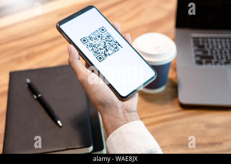 Des Menschen Hand Smartphone mit QR-Code auf dem Bildschirm, Zahlung, E-Wallet, die bargeldlose Technologie digitaler Pay ohne Geld. Konzept Stockfoto