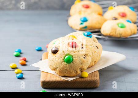 Hausgemachte frische Cookies mit farbigen runde Bonbons auf grauem Hintergrund eingerichtet. Horizontale Rahmen. Nahaufnahme der selektiven Fokus Stockfoto