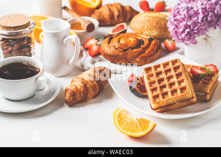 Frühstück mit Müsli, Waffeln, Croissants und Obst. Weißer Hintergrund. Stockfoto