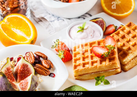 Frühstück mit Müsli, Waffeln, Croissants und Obst. Weißer Hintergrund. Stockfoto