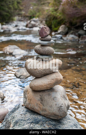 Ein Cairn der ausgewogenen Steine steht an der Seite von Wairere Stream im Tongariro Nationalpark in Neuseeland. Der Bach fließt sanft in der Rückseite Stockfoto