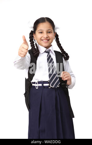 Indische Schulmädchen stehend mit Rucksack und zeigt Daumen hoch Zeichen Stockfoto