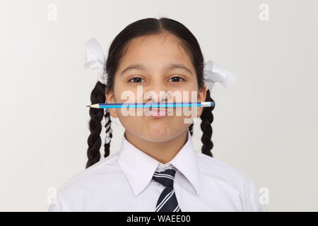 Indische Schulmädchen mit Bleistift unter ihrer Nase Stockfoto