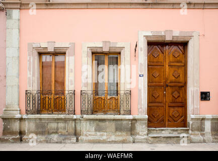 Spanischen Kolonialen Gebäude Exterieur mit geschnitzten Tür, Kastenfenster und schmiedeeiserne Geländer, Oaxaca City, Oaxaca, Mexiko lokale Architektur Stockfoto