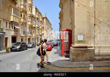 Zwei Frauen Tourist Pass ein rotes Telefon Kiosk in der Altstadt von Valletta Malta Stockfoto