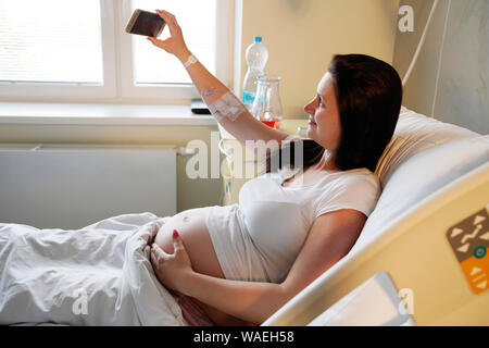 Risiko Schwangerschaft, schwangere Frau liegt im Krankenhaus und Macht selfie, Karlsbad, Tschechische Republik, Europa Stockfoto