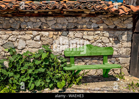 Holzbank neben einer Mauer aus Stein; Stockfoto