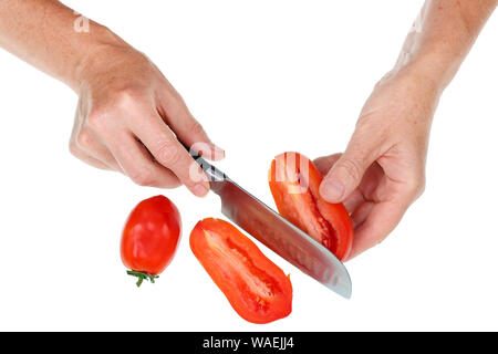 Eine alte ältere Frau hält eine rote Tomate in ihre Hände und schneidet ihn mit einem Messer. Auf weissem studio Konzept isoliert Stockfoto