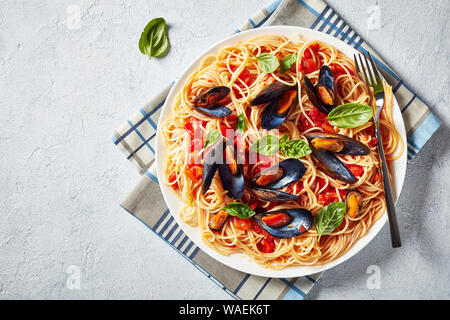 Nahaufnahme der Pasta mit Miesmuscheln in einer würzigen Tomatensauce auf einem weißen Teller auf weißem Beton Tabelle, horizontale Ansicht von oben, leeren Raum Stockfoto