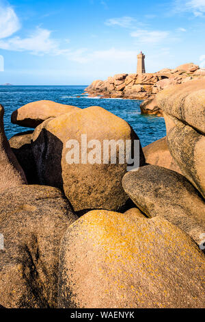 Die Ploumanac'h Leuchtturm, genannt, Ruz, an der Küste des Rosa Granits in Perros-Guirec, Bretagne, mit großen Granitfelsen im Vordergrund. Stockfoto