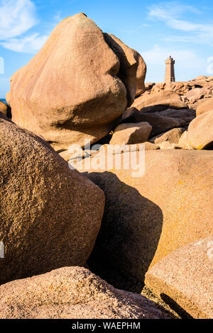 Die Ploumanac'h Leuchtturm, genannt, Ruz, an der Küste des Rosa Granits in Perros-Guirec, Bretagne, mit großen Granitfelsen im Vordergrund. Stockfoto