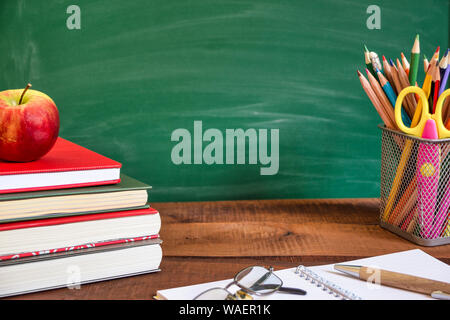 Schulmaterial, Apple und Bücher auf holztisch vor der Schule Schiefertafel. Zurück zum Konzept der Schule. Stockfoto