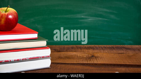 Bücher und Apple auf holztisch vor der Schule Schiefertafel. Zurück zum Konzept der Schule. Kopieren Raum auf der rechten Seite. Stockfoto