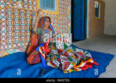 Frau in traditionellen Stoff nähen Handwerk vor einem Haus, Khavda Tourist Village, tolle Rann von Kutch Wüste, Gujarat, Indien. Stockfoto