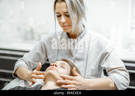 Kosmetiker, Gesichtsmassage, eine schöne Frau im Schönheitssalon. Konzept einer Lymphdrainage Therapie Stockfoto