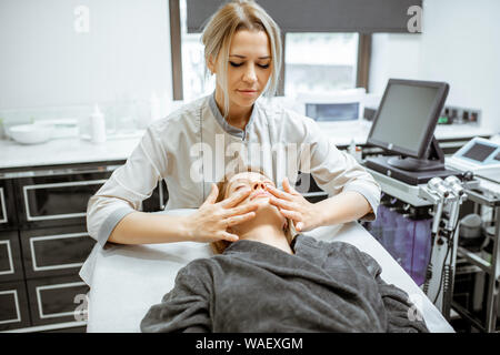 Kosmetiker, Gesichtsmassage, eine schöne Frau im Schönheitssalon. Konzept einer Lymphdrainage Therapie Stockfoto