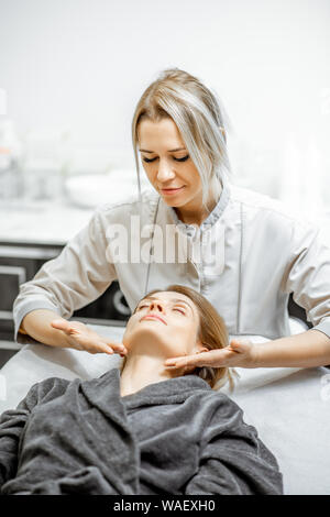 Kosmetiker, Gesichtsmassage, eine schöne Frau im Schönheitssalon. Konzept einer Lymphdrainage Therapie Stockfoto