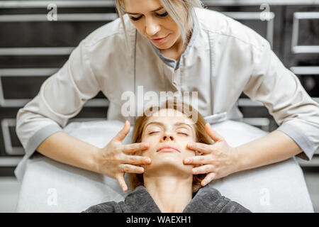 Kosmetiker, Gesichtsmassage, eine schöne Frau im Schönheitssalon. Konzept einer Lymphdrainage Therapie Stockfoto