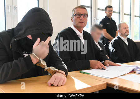 Stralsund, Deutschland. 20 Aug, 2019. Der 19-jährige Beklagte (l) zeigt seinen Mittelfinger in den Gerichtssaal des Landgerichts. Für die Ermordung der 18-jährigen Maria aus Zinnowitz auf Usedom, die 19-Jährige und eine 21-Jährige (3. von links) beim Gerichtshof haben am gleichen Tag zu beantworten. Die Staatsanwaltschaft wirft ihnen der Schleichend tötet schwangere Maria Mitte März 2019 von Mord. Quelle: Stefan Sauer/dpa-Zentralbild/dpa - ACHTUNG: Person(en) pixelated sind aus rechtlichen Gründen/dpa/Alamy leben Nachrichten Stockfoto