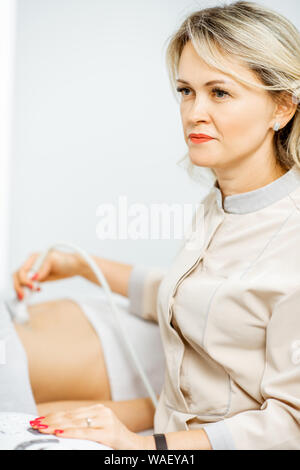 Weibliche Arzt führt eine Ultraschalluntersuchung der Becken- Frauen Organe oder zur Diagnose von der frühen Schwangerschaft an der medizinischen Büro Stockfoto