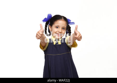 Schulmädchen stehen und zeigen Daumen nach oben Zeichen Stockfoto