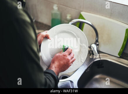 Nahaufnahme eines Menschen waschen der Keramik Teller in die Spüle Stockfoto