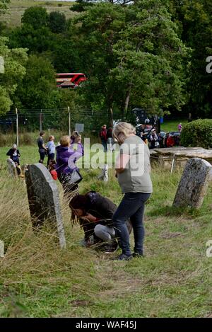 Menschen Prüfung der Grabsteine in Imber Kirchhof, Salisbury Plain auf dem jährlichen Tag der offenen Tür 17 August 2019. Stockfoto