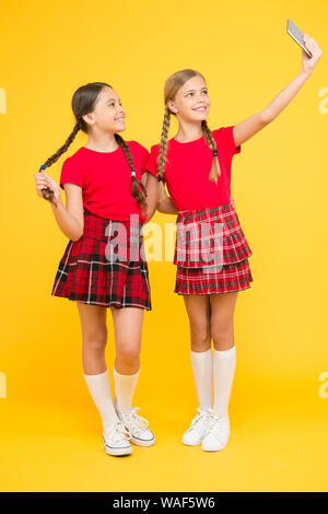 Lustige Freunde. Spaß. Schwesternschaft und Freundschaft. Glücklich wissen Tag. Kindheit Glück. Bildung Konzept. zurück zu Schule. sozialen Netzwerk. Mädchen in Uniform. kleine Mädchen selfie am Telefon. Stockfoto