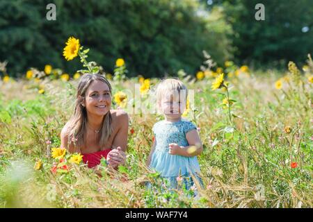 Brighton UK 20. August 2019 - zwei Jahre alte Isabella genießt einen Spaziergang durch ein Feld mit Sonnenblumen mit ihrer Mutter Harriet an Woodingdean in der Nähe von Brighton an einem schönen sonnigen Tag. Heißes Wetter ist für später in der Woche in Großbritannien vor allem in den Bank Holiday Wochenende prognostiziert. Foto: Simon Dack/Alamy leben Nachrichten Stockfoto