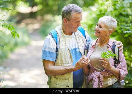Älterer Mann und seine Frau umarmt und sie lächelnd, während sie wandern in der Natur Stockfoto