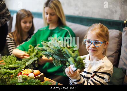 7/8-Ansicht der Familie zu Weihnachten Kranz aus Tannenzweigen, Weihnachten Kugeln und der tannenzapfen auf dem hölzernen Tisch Stockfoto