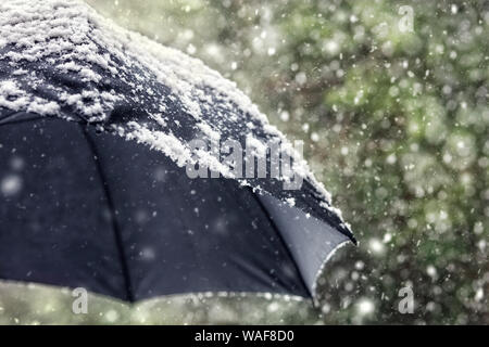 Schneeflocken fallen auf einen schwarzen Regenschirm Konzept für schlechtes Wetter, Winter oder schneit Blizzard Stockfoto