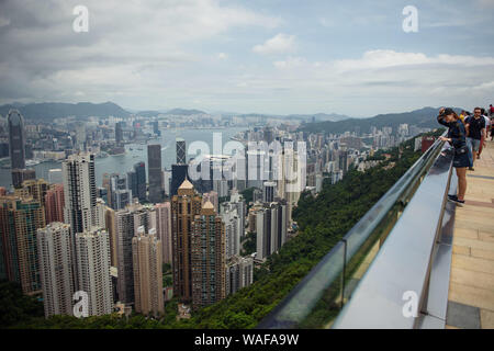 Hongkong, China. 20 Aug, 2019. Touristen stehen auf der Aussichtsplattform des Victoria Peak vor der Skyline von Hongkong. Anders als in den Wochen vor, die Proteste am Wochenende nicht zu erheblichen Unruhen führen. Die Demonstranten nicht Barrikaden zu errichten. Die Polizei verzichtete mit Gas, das als ein Zeichen der Entspannung angesehen wurde. Credit: Gregor Fischer/dpa/Alamy leben Nachrichten Stockfoto