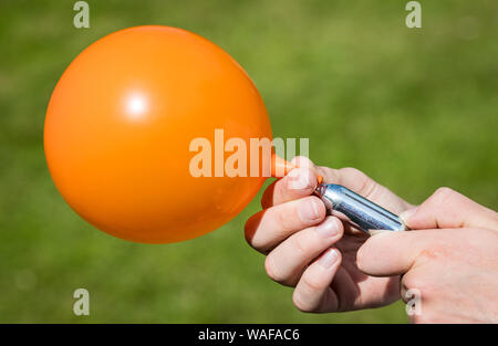 Ein Jugendlicher füllt einen Ballon mit Distickstoffoxid (Lachgas) auch als Hippie crack bekannt Stockfoto