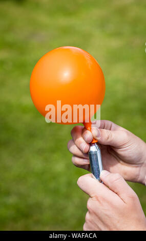Ein Jugendlicher füllt einen Ballon mit Distickstoffoxid (Lachgas) auch als Hippie crack bekannt Stockfoto