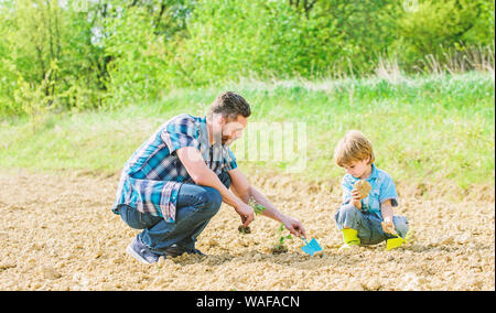 Reichen natürlichen Boden. Eco Farm. happy Earth Day. Stammbaum. neues Leben. Böden und Düngemitteln. kleiner Junge Kind helfen Vater in der Landwirtschaft. Vater und Sohn Blumen Pflanzen im Boden. Tag der Erde. Garten Bett. Stockfoto