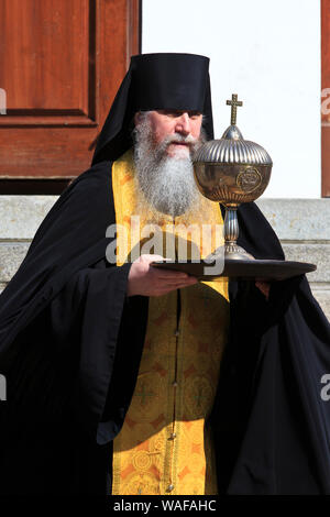 Ein russisch-orthodoxen Mönch mit einem Tablett mit Kelch nach der Messe in der Kathedrale von 1352 im Trinity Lavra in Sergiyev Posad, Russland Stockfoto