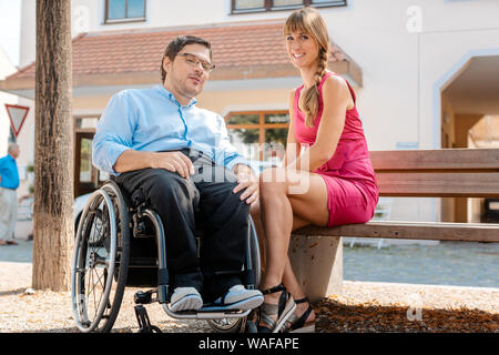 Mann im Rollstuhl und Frau essen nibbles Ausgabe Zeit Stockfoto