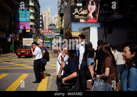 Hongkong, China. 20 Aug, 2019. Passanten warten im Stadtteil Mongkok in Kowloon Bezirk an einer Kreuzung an einer roten Ampel die Straße überqueren. Anders als in den Wochen vor, die Proteste am Wochenende nicht zu erheblichen Unruhen führen. Die Demonstranten nicht Barrikaden zu errichten. Die Polizei verzichtete mit Gas, das als ein Zeichen der Entspannung angesehen wurde. Credit: Gregor Fischer/dpa/Alamy leben Nachrichten Stockfoto