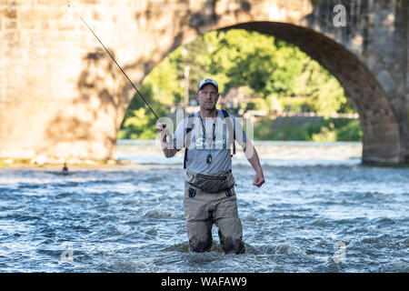 27. Juni 2019, Niedersachsen, Hann. Münden: Aik Beucken, Vorsitzender der Fischerfreunde münden, steht mit der Fliege Route für Fliegenfischen vor der alten Brücke in der Werra die Werra. Foto: Swen Pförtner/dpa Stockfoto