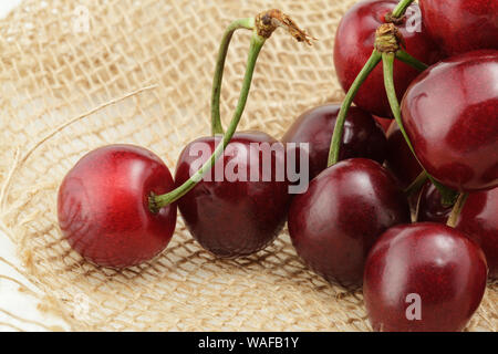 Close up of plump fresh red cherries on hessian fabric Stockfoto