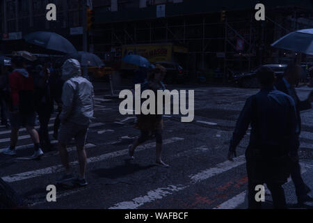 New York City, ca. 2019: Nacht über Manhattan zebrastreifen am Abend Fahrt im Regen. Poncho und Regenschirm Beläge halten Fußgänger d Stockfoto