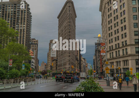 New York City, ca.2019: Flat Iron Building Breite außen zur Gründung shot street view während des morgendlichen Berufsverkehrs pendeln. Menschen gehen entlang der Seite Wal Stockfoto