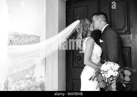 Der Kuss. Braut und Bräutigam Küsse zärtlich vor der Kirche Portal.