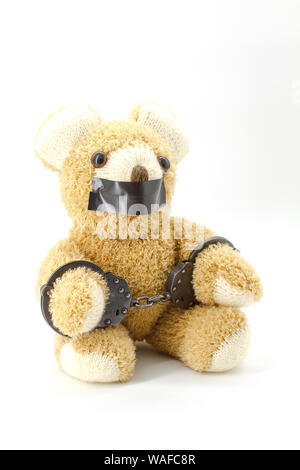 Plüsch Teddybär mit Handschellen auf weißem Hintergrund Stockfoto