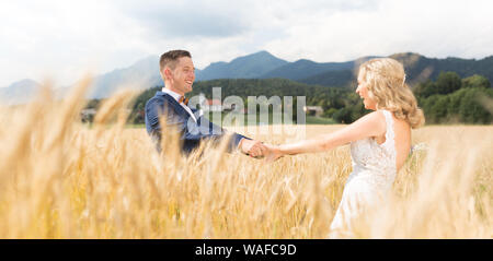 Bräutigam und Braut, Hände halten in Weizen Feld irgendwo in der slowenischen Landschaft. Stockfoto