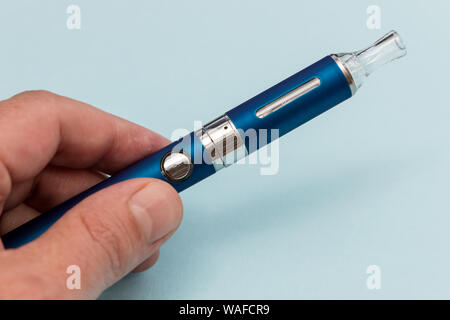 Hand mit vape pen Metall elektronische Zigarette mit vaping blauer Hintergrund Stockfoto