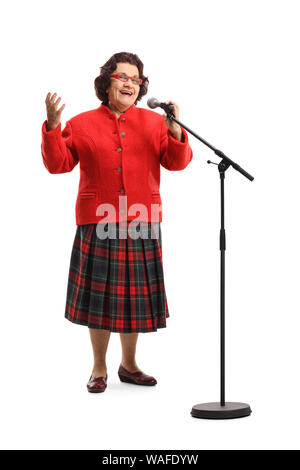 In voller Länge Porträt einer älteren Dame in einem roten Mantel singen auf ein Mikrofon auf weißem Hintergrund Stockfoto