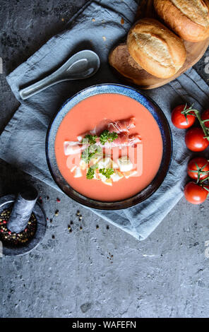 Salmorejo, kalte Tomatensuppe mit Serrano Schinken und Eier in eine keramische Schüssel, serviert mit Gebäck Stockfoto